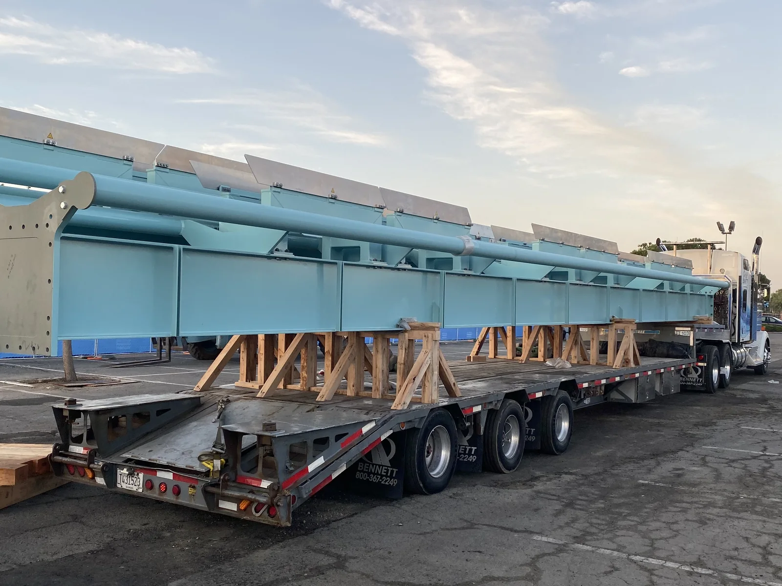 Long fabricated steel assembly supported on a flatbed trailer