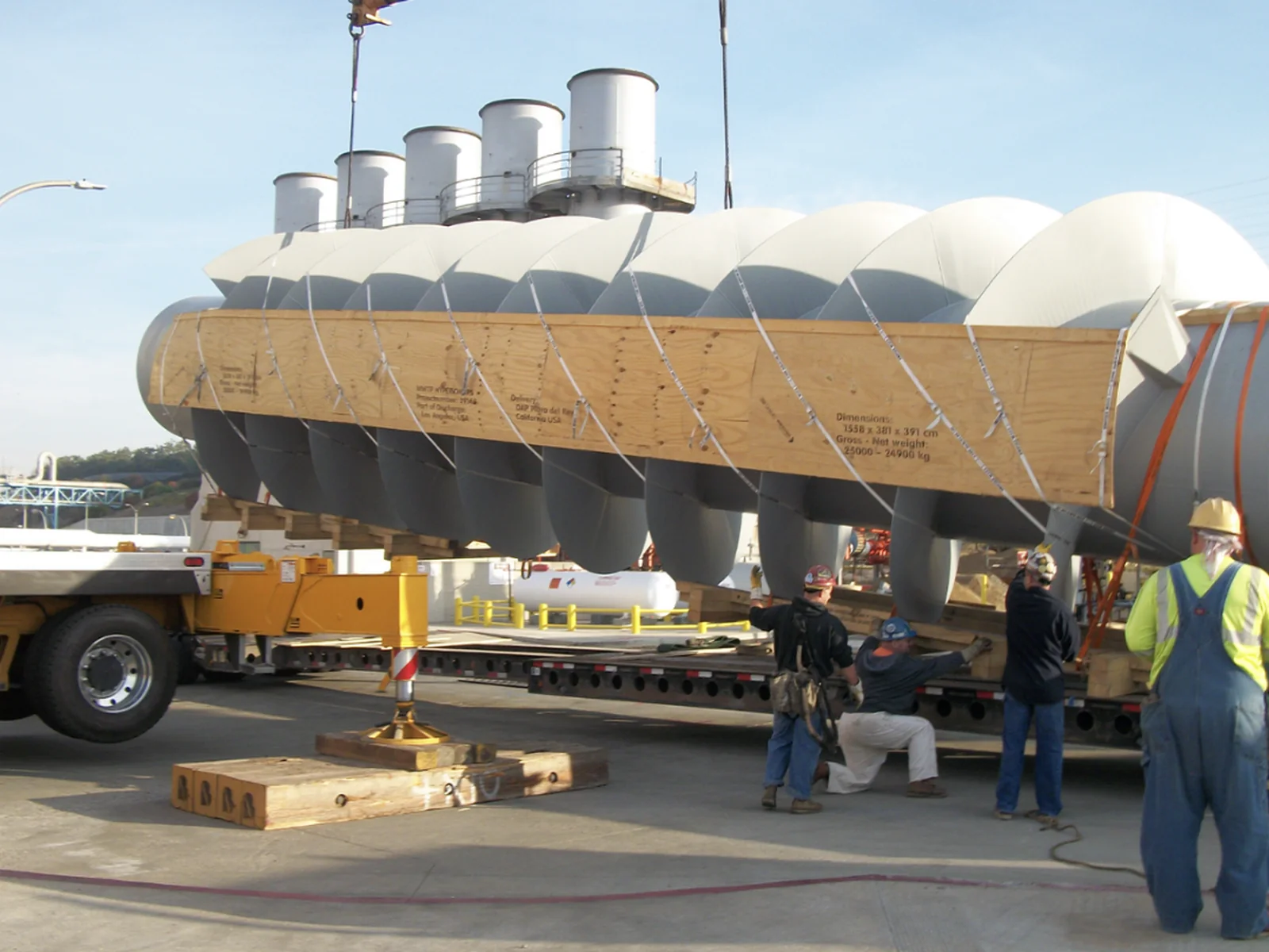 Crew unloading a large industrial auger assembly from a transport trailer