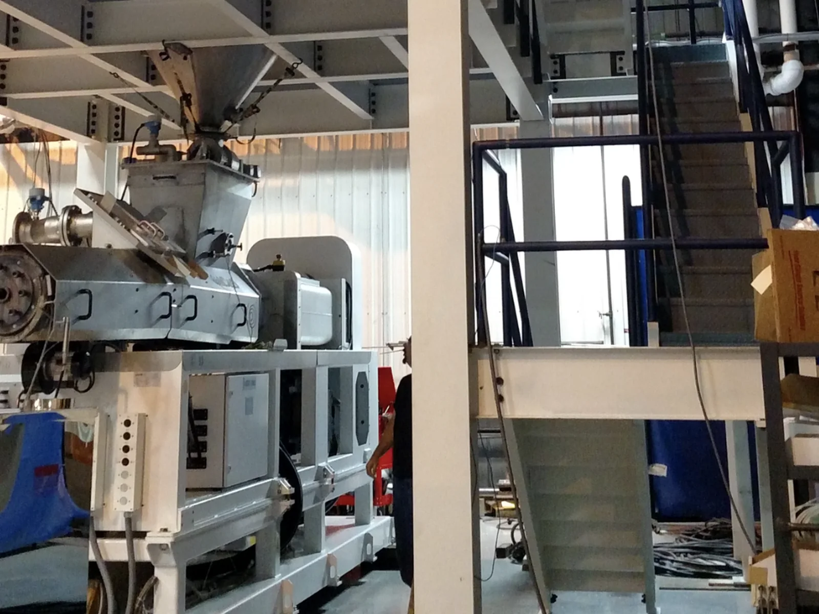 Industrial production machine installed beneath a material feed system