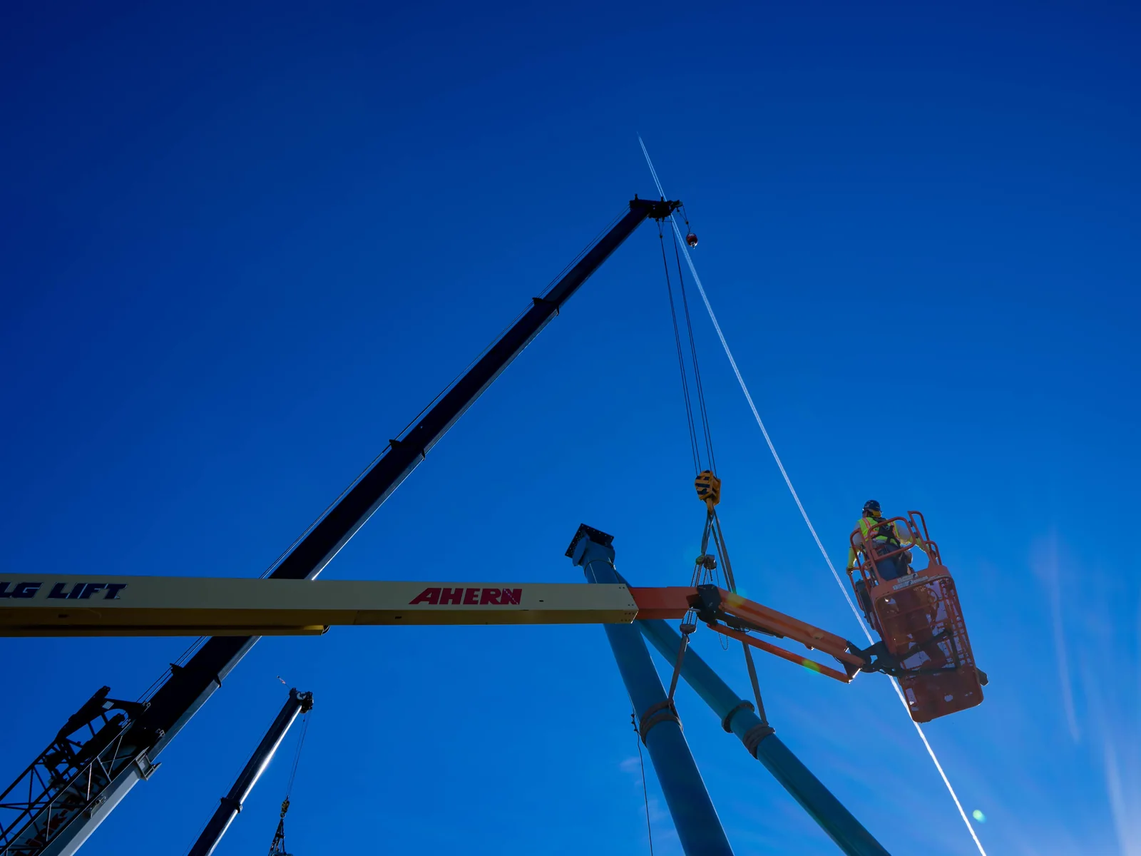 Crew setting a large tubular steel support column by crane