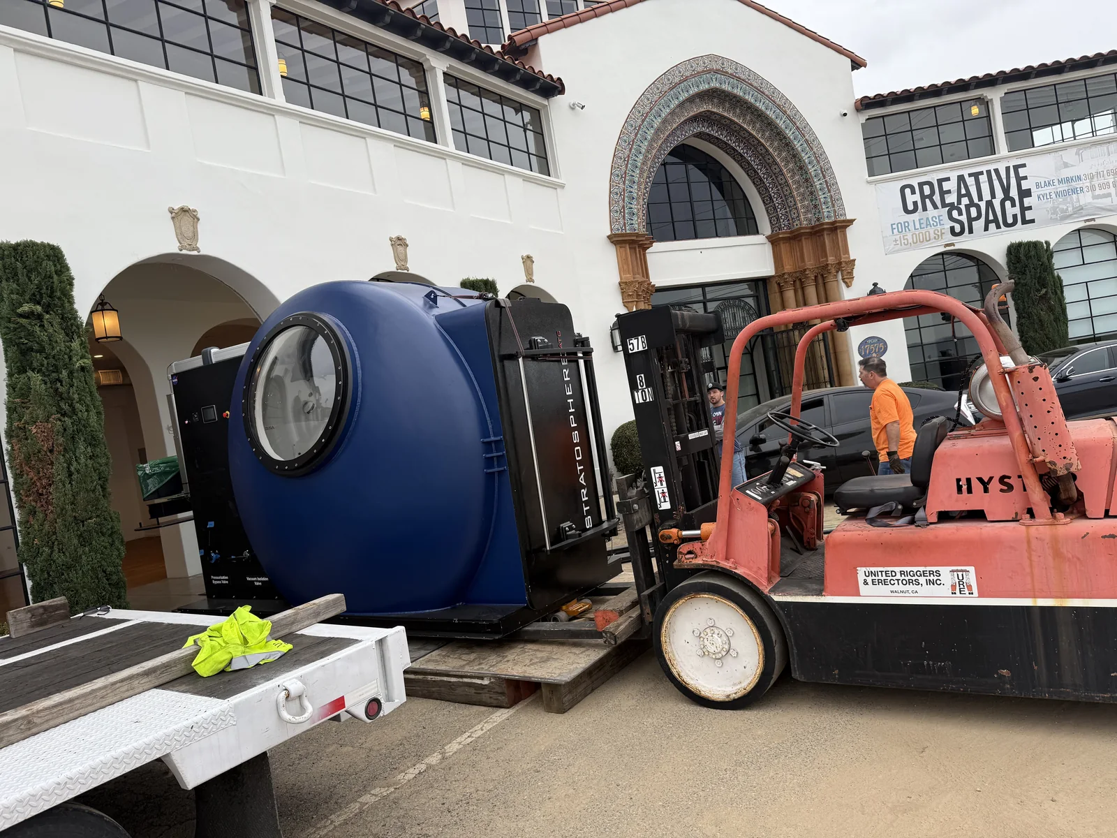 Large vacuum chamber being moved from a flatbed trailer by forklift