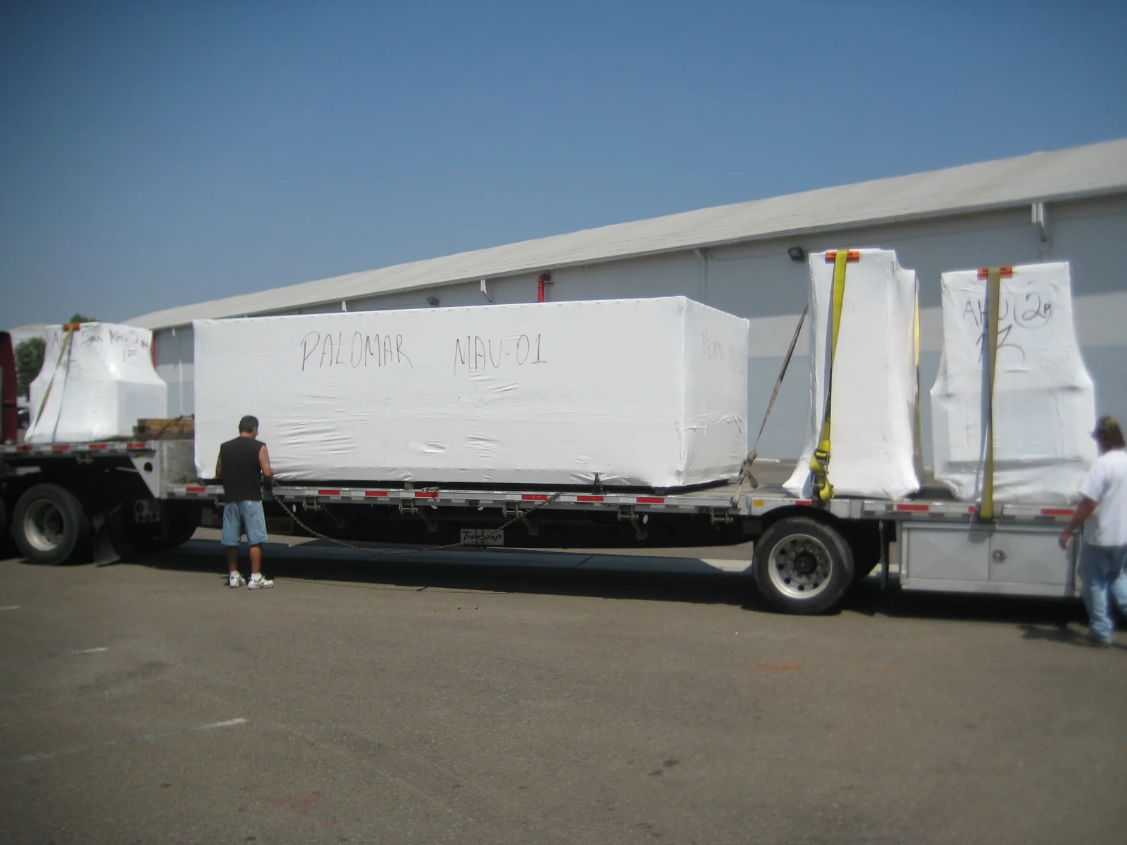 Wrapped industrial equipment secured on a flatbed trailer