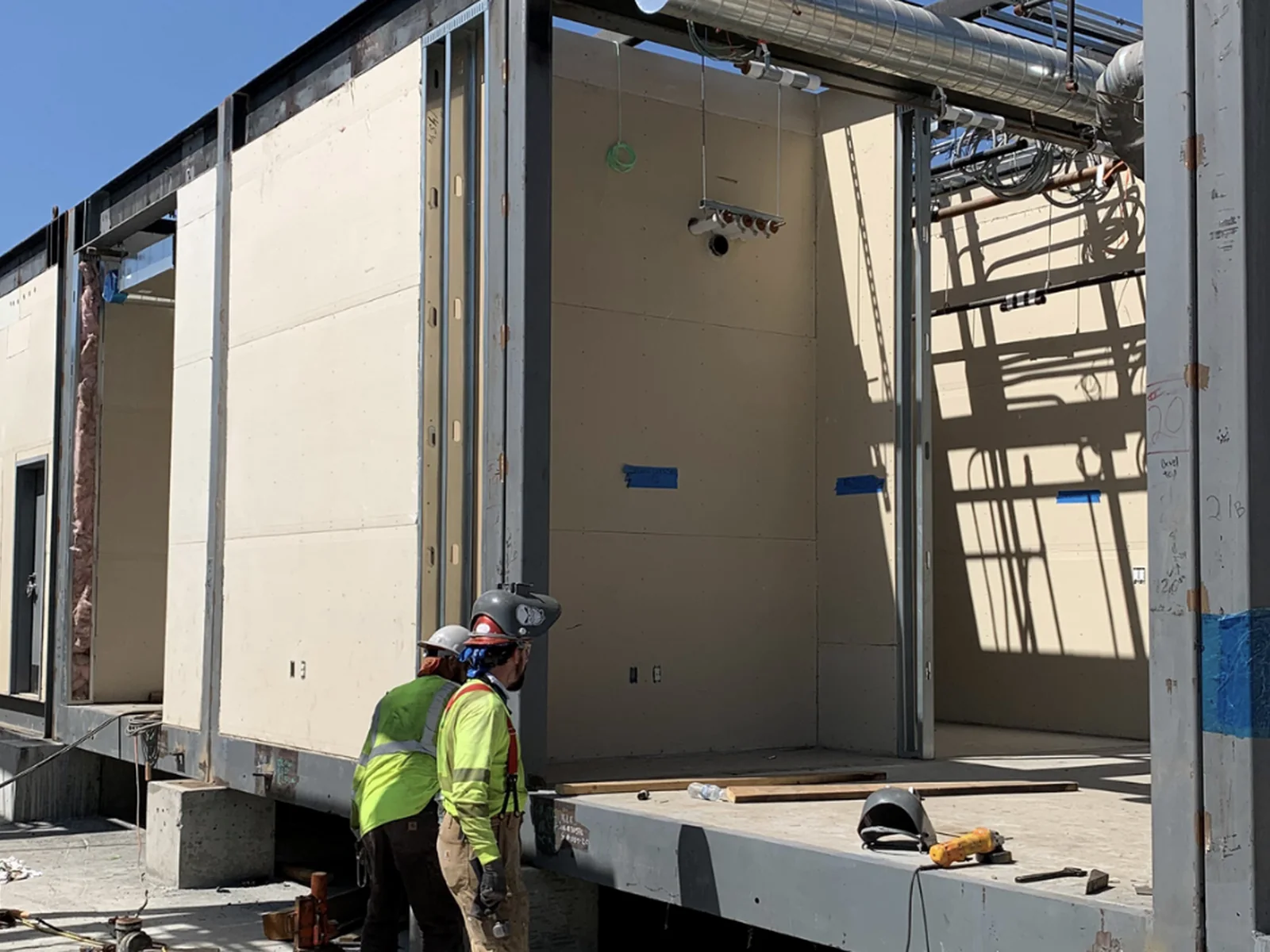 Workers aligning adjacent modular building sections during assembly