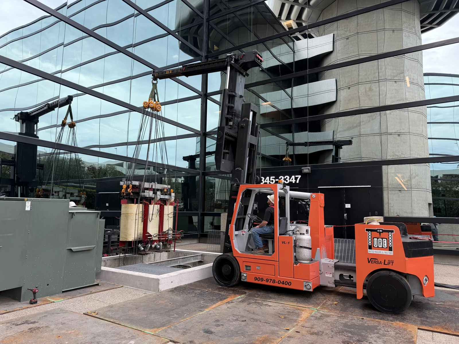 URE Versa-Lift lowering a transformer onto an exterior equipment pad
