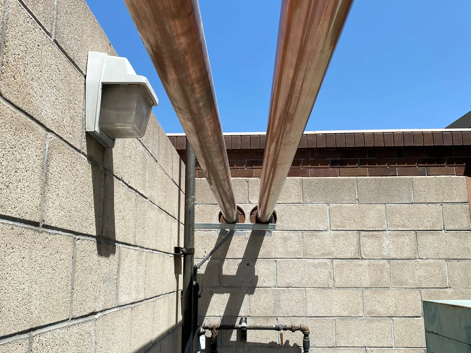 Supported copper piping installed along an exterior block wall