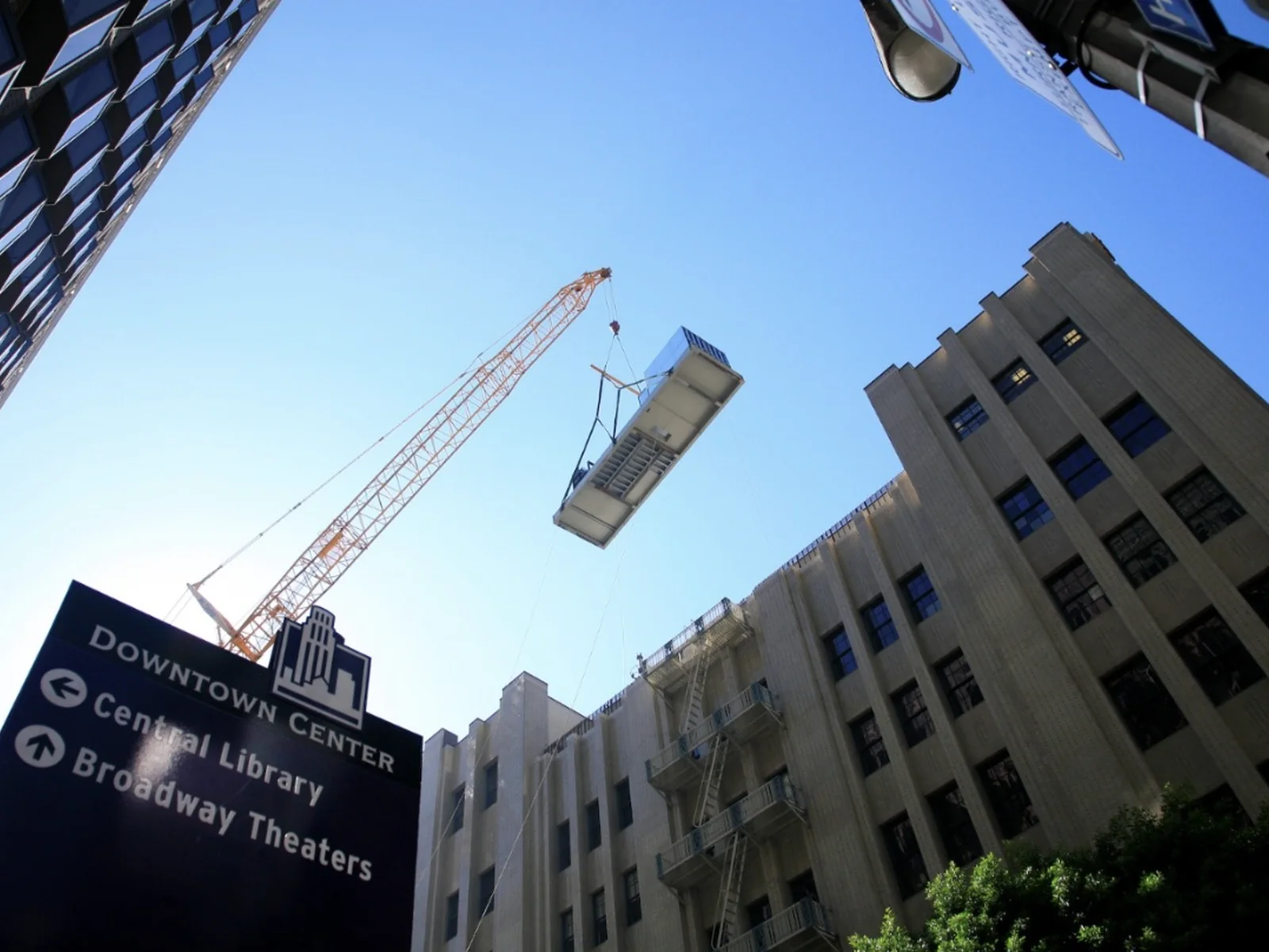 Crane lifting a large rooftop equipment unit in downtown Los Angeles