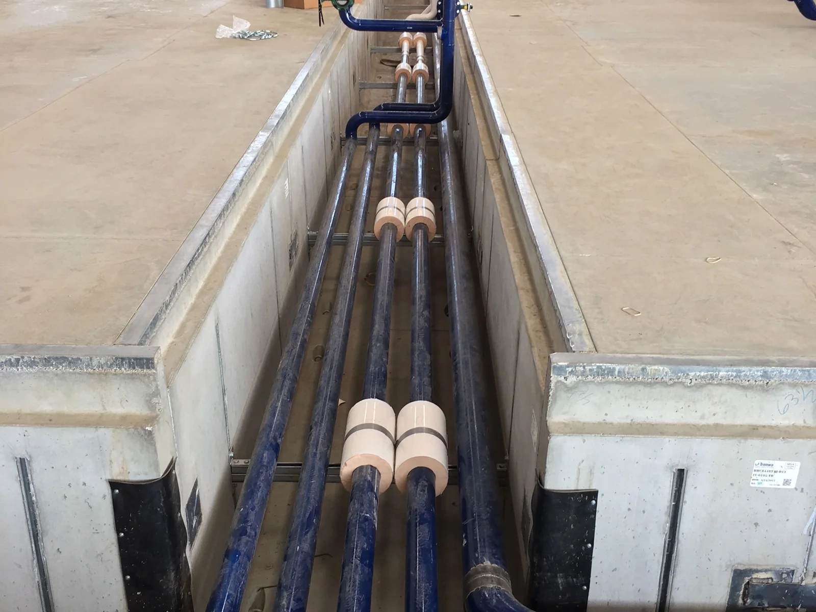 Close view of blue process piping routed through a utility trench