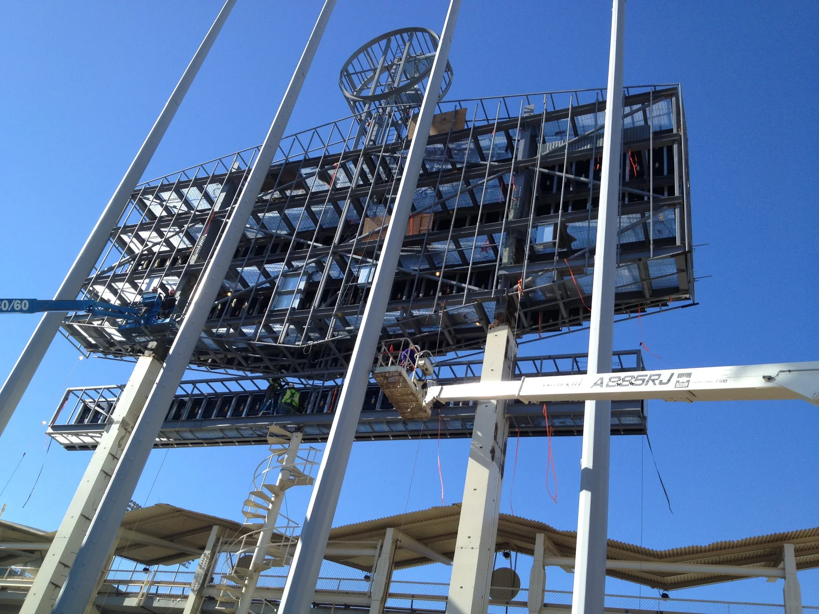 Large structural steel frame under construction above an occupied venue