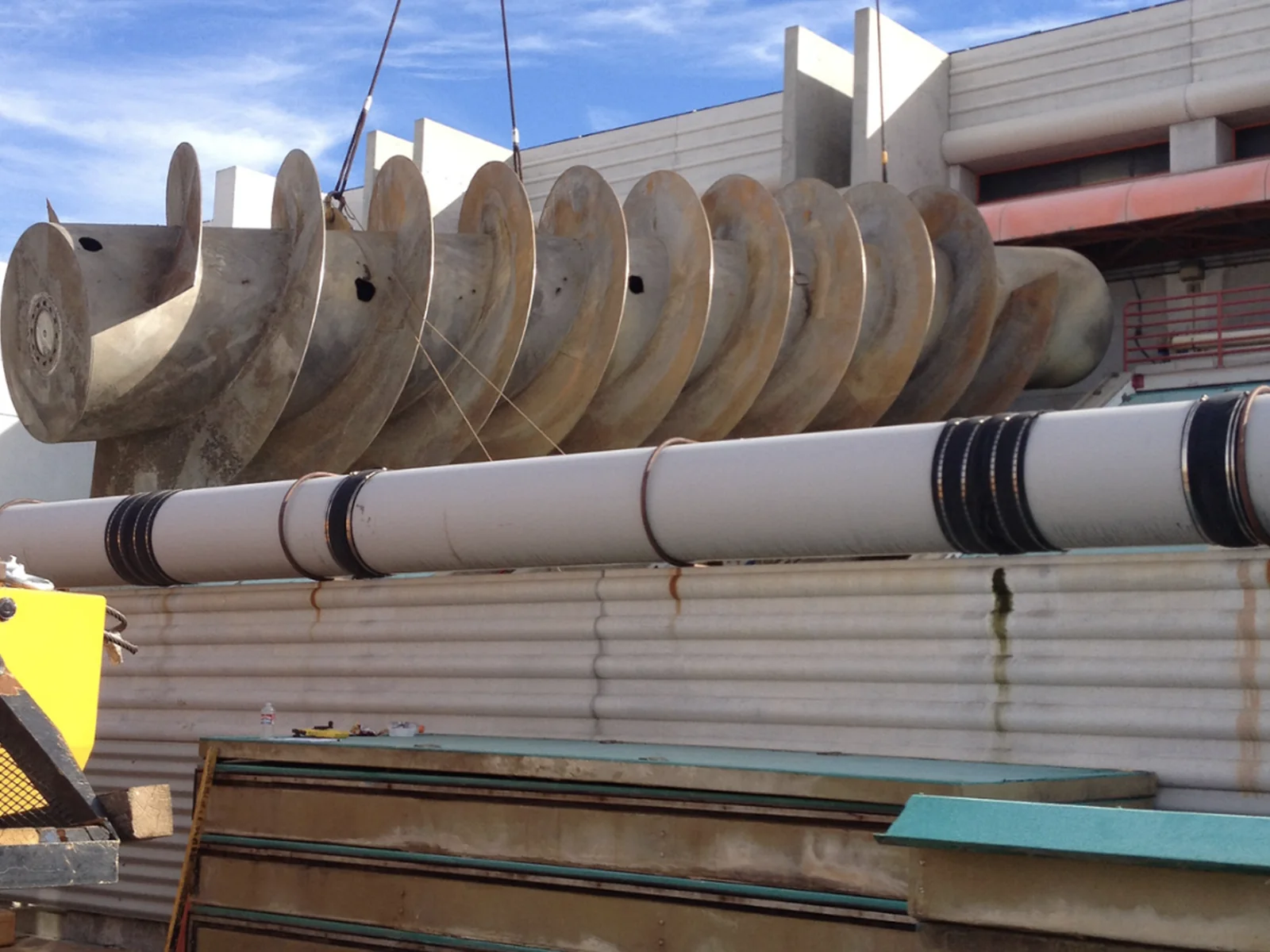 Large industrial auger being lifted from a process facility by crane