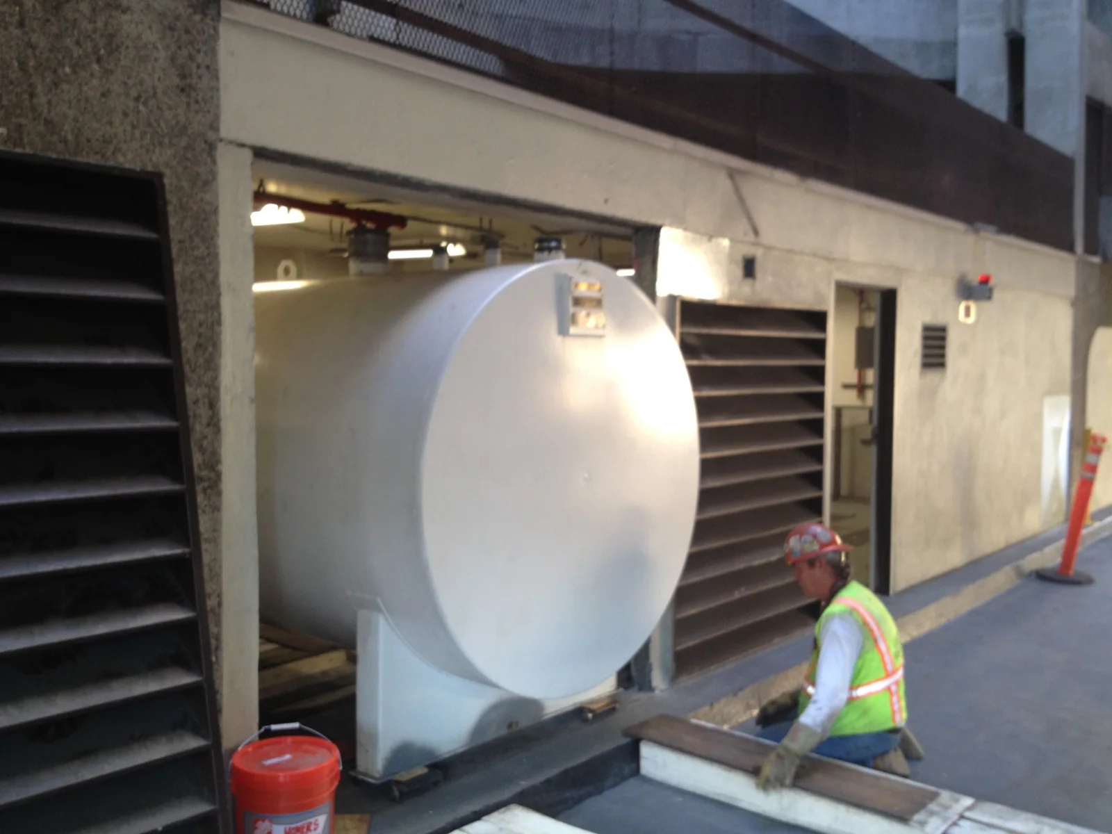 Crew moving a horizontal storage tank through a facility opening